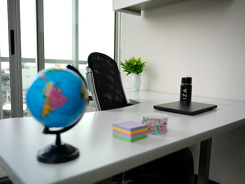 Escritorio con globo terráqueo y libros junto a ventana – Iza Office Club