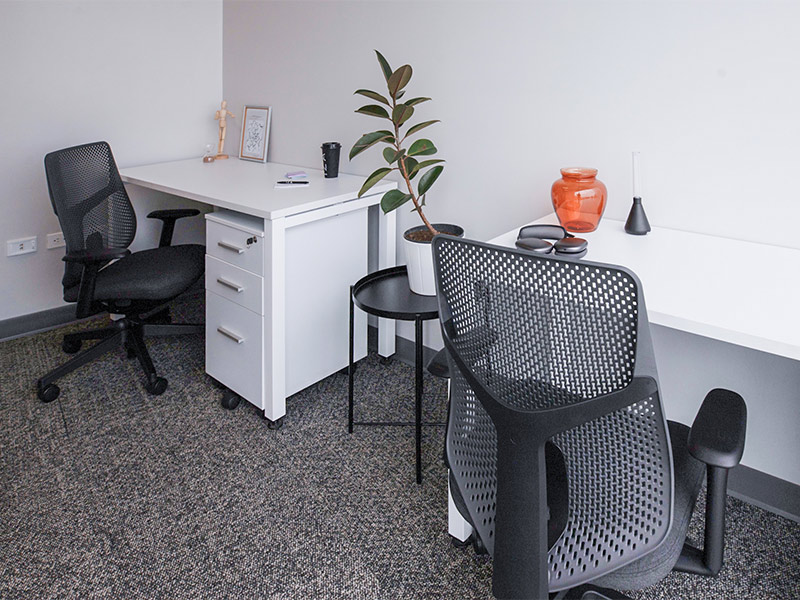 Dos estaciones de trabajo de oficina con escritorios blancos, sillas ergonómicas y decoración minimalista en Inxignia, oficina en renta en Puebla