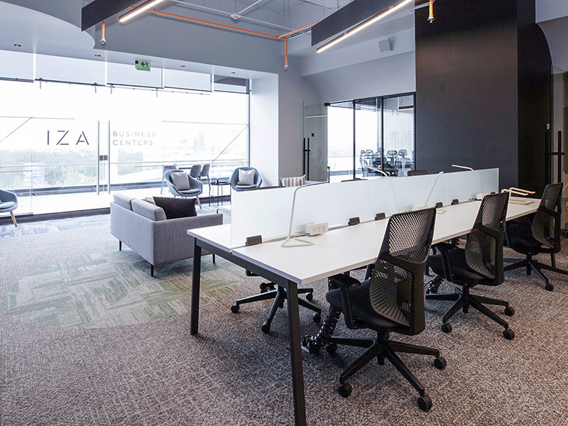 Espacio de oficina abierta de IZA con escritorios compartidos y área de lounge, mucha luz natural en Inxignia, oficina en renta en Puebla