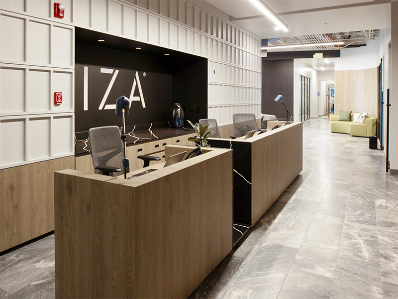 Lobby de oficinas IZA con diseño contemporáneo, áreas de atención y camino hacia espacios de trabajo en Inxignia, oficina en renta en Puebla