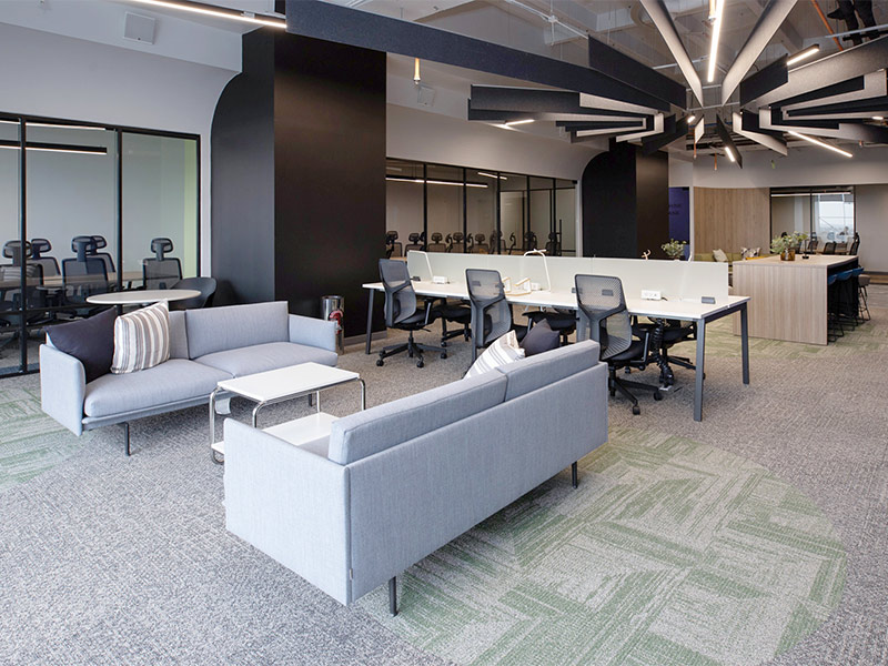 Espacio de coworking moderno: sofás, mesas de trabajo compartidas y zonas privadas con paneles de vidrio en Inxignia, oficina en renta en Puebla