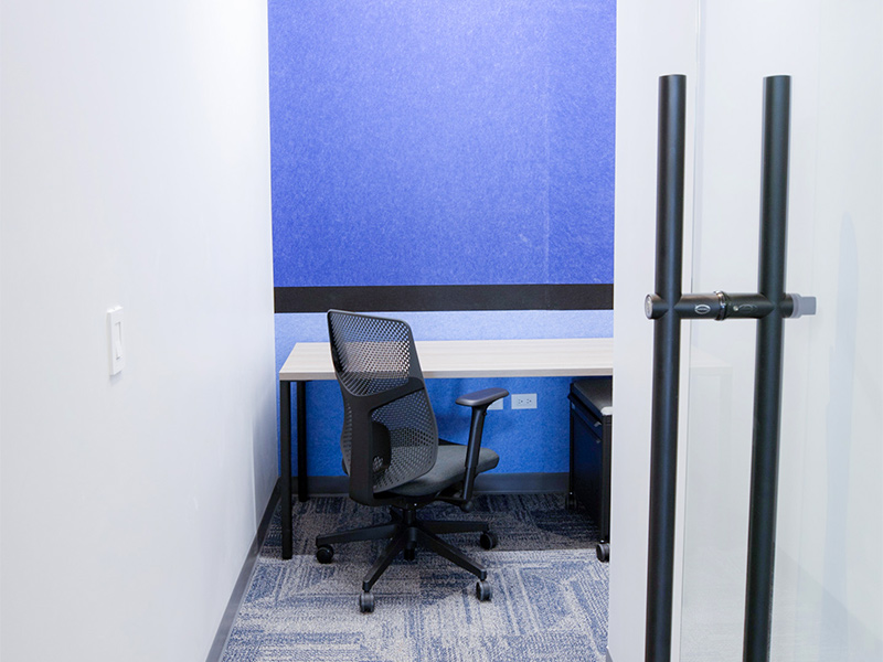 Pequeña oficina o cabina privada con escritorio, silla y panel acústico azul, ideal para concentración en Inxignia, oficina en renta en Puebla