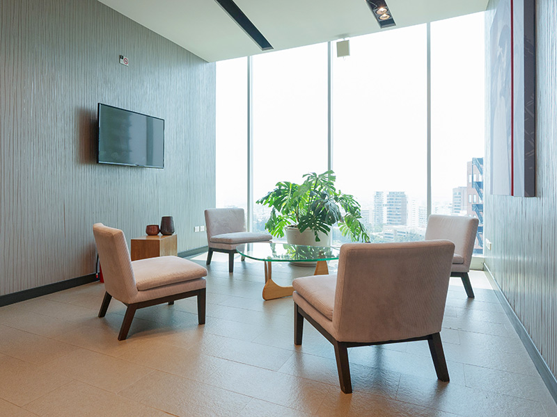 Área de espera moderna con ventanales grandes, sillas cómodas y plantas con vista a la ciudad de Guadalajara en Punto Sao Paulo, oficina en renta en Guadalajara
