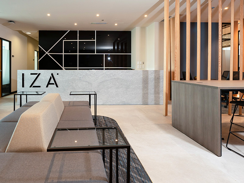 Recepción de IZA Business Center con mostrador de mármol y logo, área de lounge con sofás en Punto Sao Paulo, oficina en renta en Guadalajara