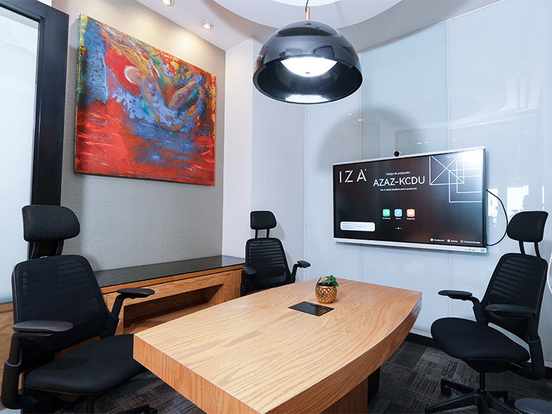 Sala de juntas IZA con pantalla, mesa de madera, sillas ergonomícas y arte abstracto moderno en la pared en Punto Sao Paulo, oficina en renta en Guadalajara
