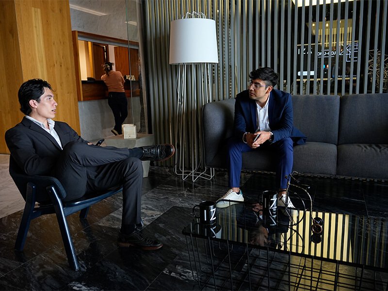 Dos hombres conversando sentados en sillones – Iza Office Club