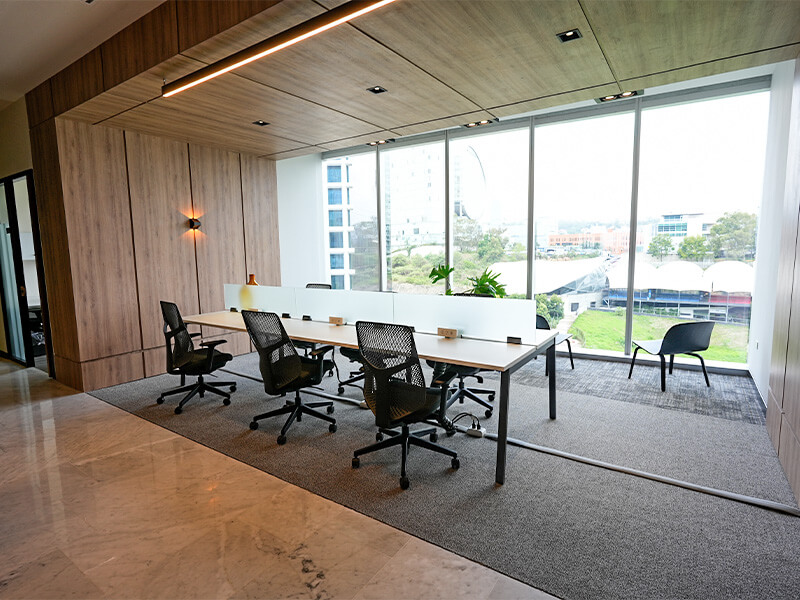 Sala de juntas con mesa larga junto a ventanal con vista a árboles – Iza Office Club