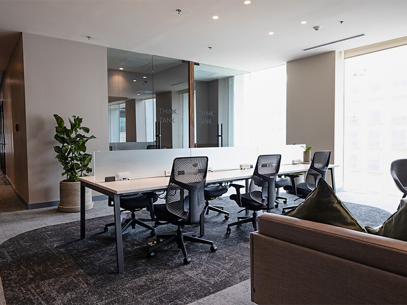 Sala de juntas con mesa y sofá café junto a ventanal – Iza Office Club