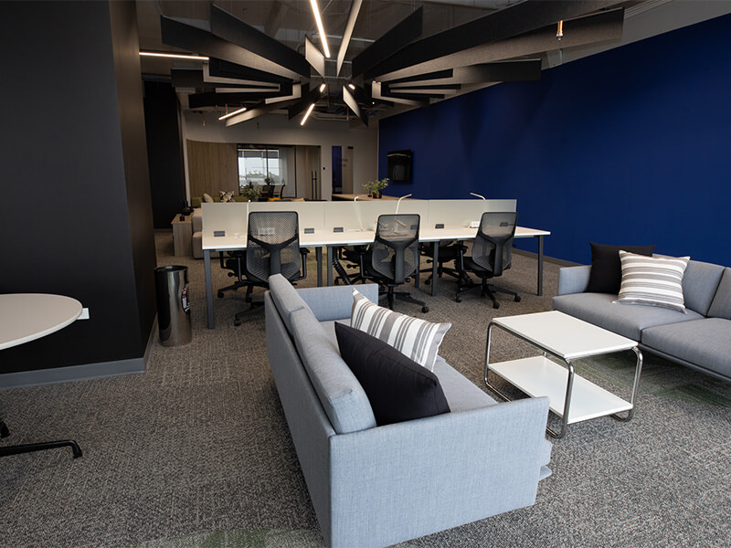 Área de lounge con sofás grises y pared azul – Iza Office Club