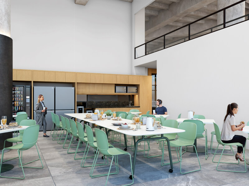 Espacio de cafetería en URBAN CENTER CANCUN con mesas largas, sillas verdes y varias personas descansando y tomando café.