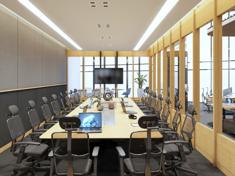 Fotografía del interior de IZA Urban Center Cancún, mostrando una moderna sala de juntas equipada con una larga mesa de madera, múltiples sillas ergonómicas, laptops y una pantalla al fondo, delimitada por una estructura de paneles de madera y cristal.